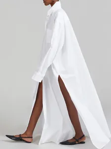 Detailed side view of a long white French-style shirt dress featuring high side slits
