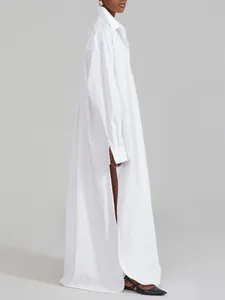 Full-length side profile of an oversized white shirt dress featuring a high slit.