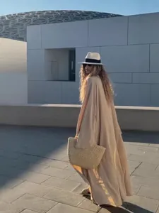 Elegant beige long cardigan dress for women in minimalist autumn style with a straw bag