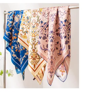 Detail view showing multiple colors of luxury silk square scarves with floral prints.