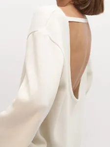 Détail d'un pull en maille dos nu crème au style minimaliste et décontracté chic