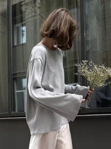 Vue détaillée d'un pull en coton gris à maille lâche avec un bouquet de fleurs séchées