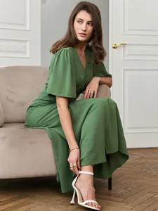 Elegant green short-sleeved maxi dress with textured fabric shown on a sitting model