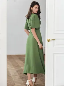 Elegant green short-sleeve maxi dress for summer on a model standing by a door.