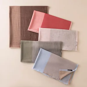 Detailed view of lightweight herringbone wool scarves in various soft colorblocks.