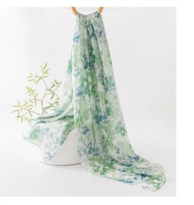 Dettaglio di una sciarpa di seta leggera con stampa floreale verde su fondo bianco