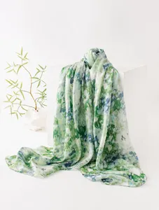 Dettaglio di sciarpa lunga in 100% seta di gelso con stampa floreale verde e drappeggio