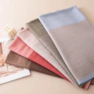 Detailed view of folded wool scarves with herringbone jacquard texture in pastel colors