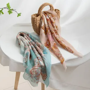 Detailed view of floral printed scarves draped over a white table and straw bag