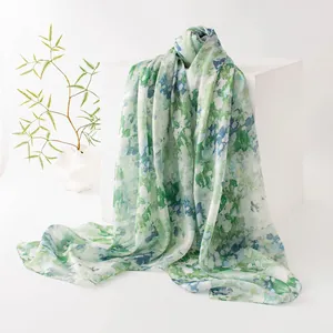 Elegante sciarpa in seta a fiori verdi e blu drappeggiata su un piedistallo minimalista