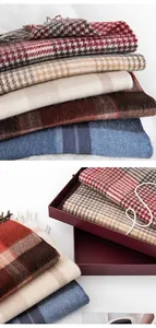 Detail view of various British style plaid wool scarves stacked and in premium gift box packaging