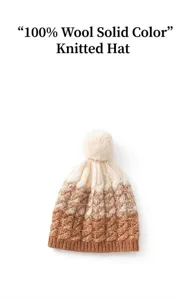 Detail view of a 100% wool knitted beanie hat with a fluffy pom-pom in camel color