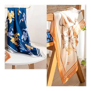 Elegant camellia floral print silk square scarves displayed on a wooden chair and table.