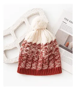 Macro view of a soft two-tone wool knit beanie featuring a fuzzy pom-pom detail.