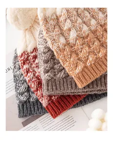 Close-up view of colorful sheep wool knit beanies with cable patterns and soft pom-poms