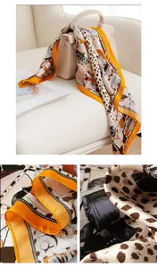 Detail of orange leopard print silk scarf showing satin texture and fine stitching