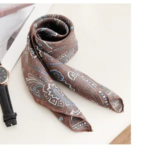 Close-up detail of the intricate paisley pattern on a brown and blue mulberry silk scarf