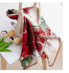Vista dettagliata di un foulard in seta con stampa a rose rosse su una borsa crema.