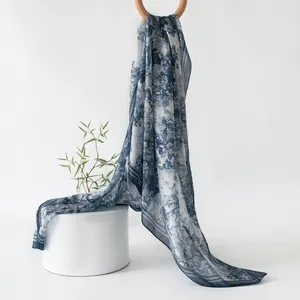 Full view of an elegant blue Toile de Jouy print silk scarf draped on a white pedestal