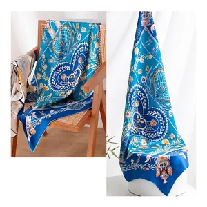 Elegant blue silk scarf featuring white heart and floral patterns displayed on a chair