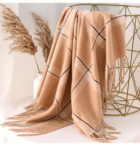 Close-up detail of a thickened beige checkered scarf with elegant fringed edges for winter.