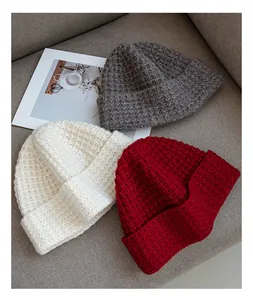 Primer plano de gorros de punto a cuadros en rojo blanco y gris sobre fondo suave