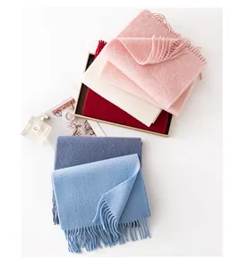 Multiple colors of soft wool scarves with tassels arranged on a clean white background.