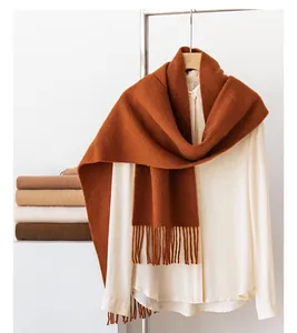 Close-up of a caramel sheep wool scarf with tassels draped on a white shirt