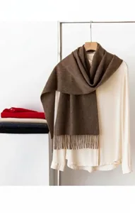 Écharpe en cachemire marron drapée sur une blouse blanche, texture douce et franges.