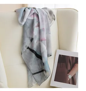 Elegant mulberry silk scarf with ink-wash magnolia print draped over a luxury chair.