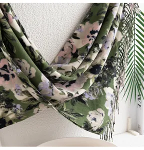Vista dettagliata di una sciarpa a fiori verdi effetto cashmere con frange morbide.