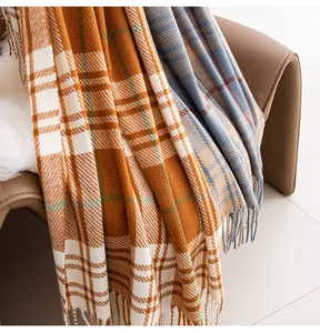 Detailopname van zachte geruite herfst-wintersjaals met kwastjes over een leren stoel