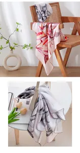 Detailed close-up of premium floral print silk scarf styled on a chair and bag