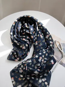 Detail view of navy blue mulberry silk scarf with delicate floral print texture.