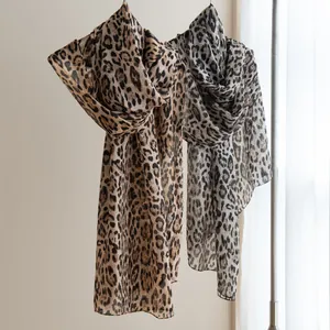 Lightweight leopard print silk scarves in brown and grey hanging gracefully on a rack