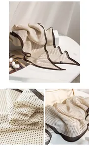 Dettaglio macro di una sciarpa in seta beige con eleganti pois marroni