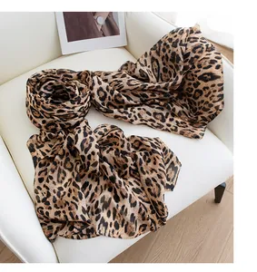 Detail shot of a stylish leopard print silk scarf on a white chair, lightweight texture.