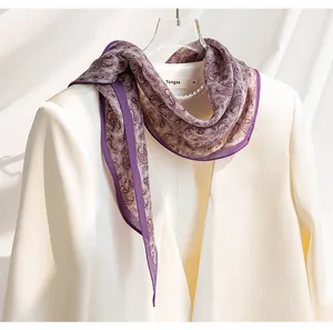 Detaillierte Nahaufnahme des lila Paisley-Seidenschals auf einem weißen Blazer