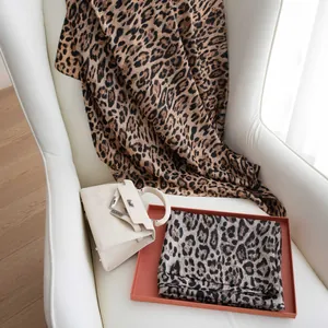 Elegant leopard print silk scarf draped on a white armchair with luxury fashion props