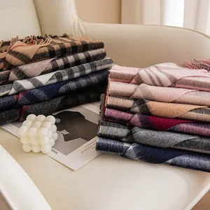 Selection of cozy checkered wool scarves for women neatly stacked on a white armchair