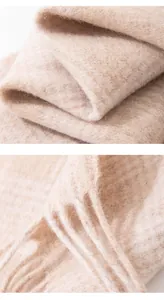 Close-up of a soft 100% wool plaid scarf with delicate fringes in creamy pink tones