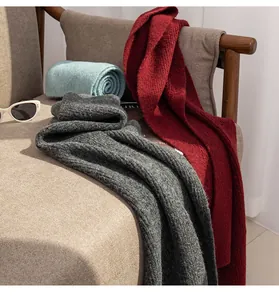 Gros plan de larges écharpes en laine unies avec une texture tricotée douce sur une chaise