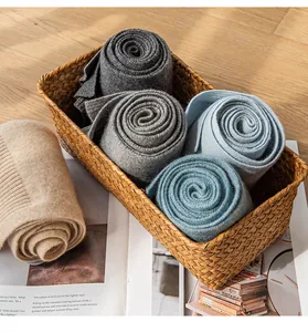 Detailed view of colorful rolled knitted cashmere scarves inside a decorative woven basket