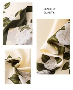 Detailed view of cream silk scarf featuring elegant white rose pattern and dark green hem