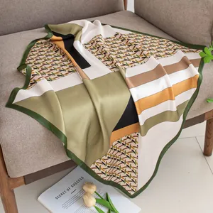 Elegant silk square scarf with geometric patterns artistically draped on a gray sofa.