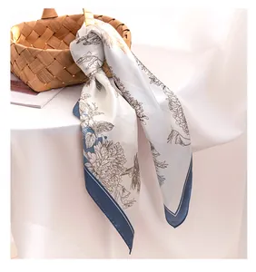 Elegant floral print silk-like square scarf tied to a woven basket under soft natural lighting