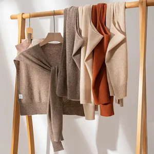Elegant cashmere knit shawls in various colors displayed on a wooden rack.