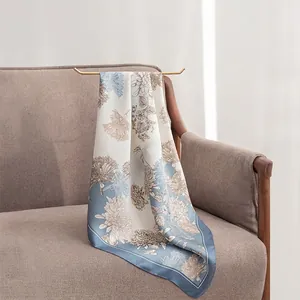 Elegant light blue floral 70cm square faux silk scarf draped over a sofa armrest