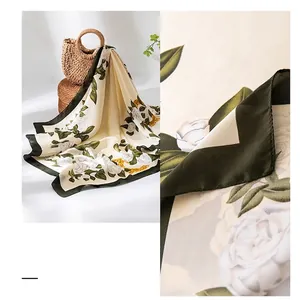 Elegant silk-like scarf with white rose prints and dark green borders in soft drape.