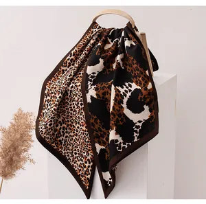 Elegant leopard print silk-wool ribbon scarf draped over a stylish beige handbag.